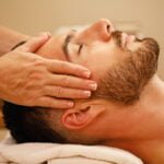 Close-up of man getting head massage and relaxing with eyes closed at the spa.